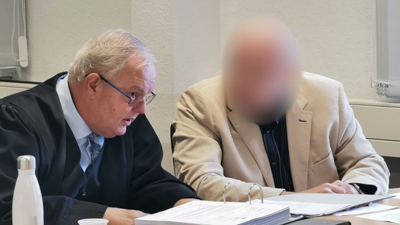 Ein Professor sitzt neben seinem Verteidiger in einem Gerichtssaal. © NDR Foto: Wieland Gabcke