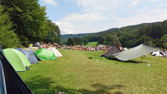 Zelte stehen auf einer Wiese umrandet von Wald. © NDR Foto: Marco Schulze