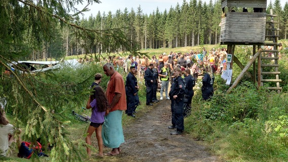 Das Bild zeigt Polizistinnen und Polizisten, die mit Teilnehmenden eines Hippie-Camps im Harz nahe Bad Grund und Clausthal-Zellerfeld sprechen. © NDR Foto: Marco Schulze