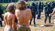 Zahlreiche Polizeibeamte stehen beim "Rainbow Gathering" neben Campern. © Landkreis Goslar/Stefan Sobotta Foto: Stefan Sobotta