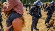 Zahlreiche Polizeibeamte stehen beim "Rainbow Gathering" neben Campern. © Landkreis Goslar/Stefan Sobotta Foto: Stefan Sobotta