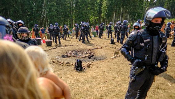 Polizisten stehen um eine Feuerstelle im Camp der "Rainbow Family" im Harz © Landkreis Goslar 