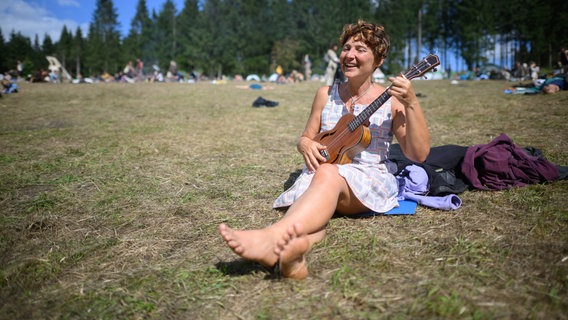 Eine Frau spielt Ukulele und singt Lieder bei einem Zeltlager. © dpa-Bildfunk Foto: Julian Stratenschulte