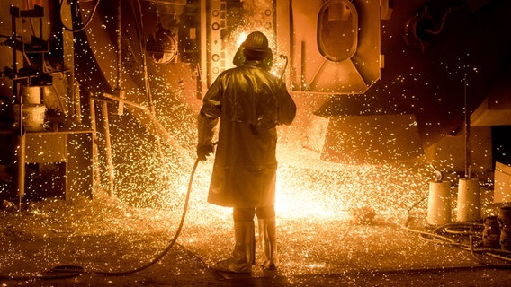 Ein Mitarbeiter in Schutzkleidung arbeitet auf dem Gelände der Salzgitter AG an einer Stahlpfanne. © picture alliance Foto: Julian Stratenschulte