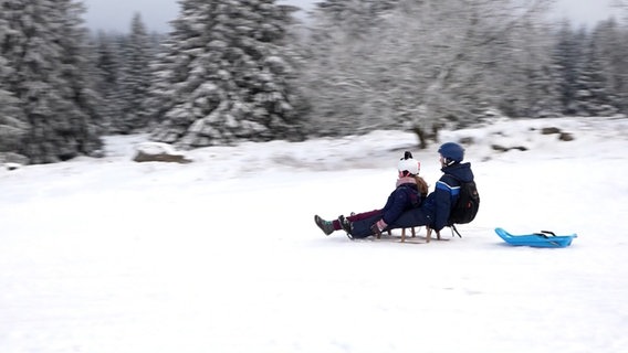 Zwei Menschen rodeln auf einem schneebedeckten Rodelberg in Torfhaus. © Nord-West-Media TV 