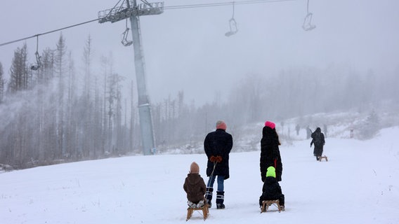 Menschen sind am Hexenritt mit Schlitten im Schnee unterwegs. © dpa Foto: Matthias Bein