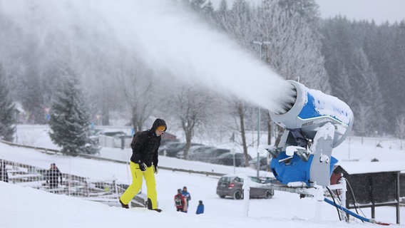 Eine Frau neben einer Schneekanone am Wurmberg. © dpa Foto: Matthias Bein