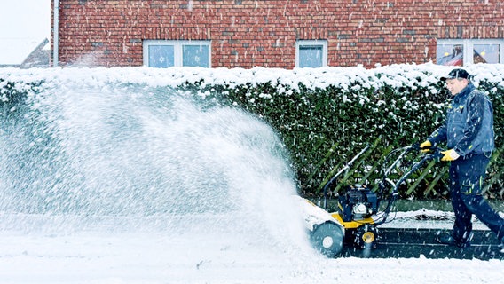 Ein Mann räumt mit einer Schneefräse in Braunschweig den Gehweg frei . © NDR Foto: Sabine Hausherr