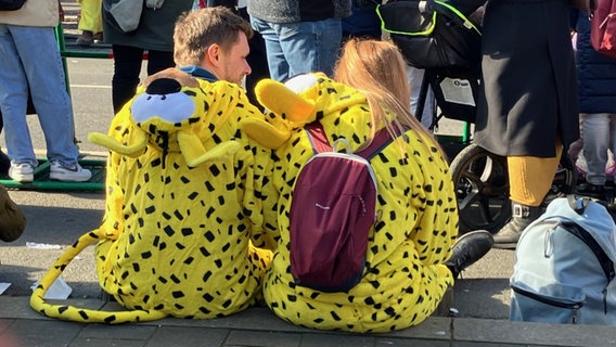 Ein Mann und eine Frau in Marsupilami-Kostümen sitzen beim Schoduvel in Braunschweig am Straßenrand. © NDR Foto: Ute Andres