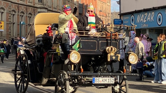 zwei verkleidete Menschen in einem sehr alt aussehenden offenen Auto beim Umzug zum Schoduvel in Braunschweig 2025 © NDR Foto: Ute Andres