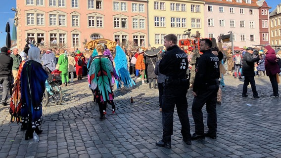 Zwei Polizisten schauen beim Schoduvel in Braunschweig kostümierten Menschen beim Feiern zu. © NDR Foto: Ute Andres