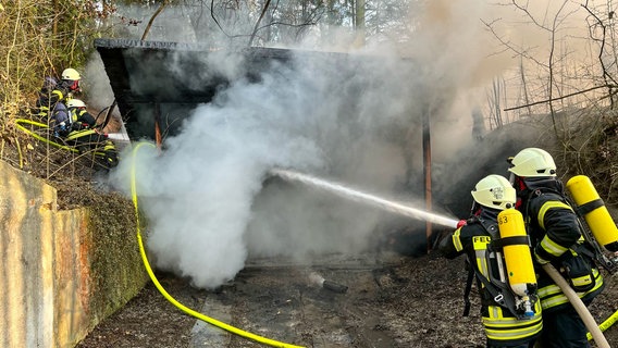 Feuerwehrleute richten einen Wasserstrahl auf den brennenden Schießstand des Schützenvereins. © FFW Friedland Foto: FFW Friedland