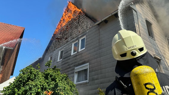 Ein Feuerwehrmann löscht ein brennendes Haus. © Kreisfeuerwehr Northeim Foto: Konstantin Mennecke