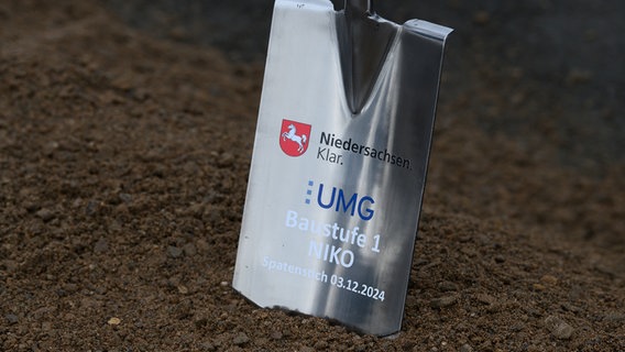 Ein Spaten steckt vor dem symbolischen Spatenstich für den Neubau der Universitätsmedizin Göttingen in der Erde. © dpa Foto: Swen Pförtner