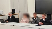 Zwei Verteidiger sitzen mit dem angeklagten Ehepaar, das seine erwachsene Tochter beziehungsweise Stieftochter schwer sexuell missbraucht haben soll im Gerichtssaal. © dpa Foto: Christian Brahmann