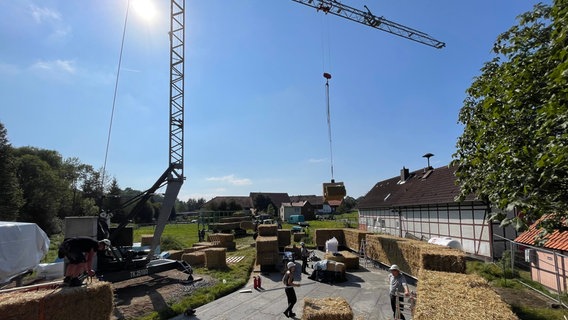 Ein schwerer Strohballen schwebt an einem Kran. © NDR Foto: Jan Fragel