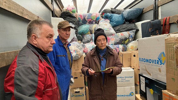 Der Ukrainische Lkw-Fahrer Boris Zhwk, Sven Rathgeber und Ingrid Rathgeber stehen in einem Lkw voller Güter. © NDR Foto: Bärbel Wiethoff