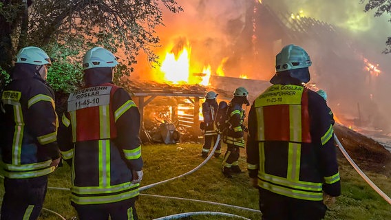 Einsatzkräfte der Feuerwehr stehen vor einem brennenden Gebäude. © Feuerwehr Goslar 