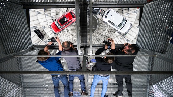 Fotojournalisten fotografieren Neuwagen von Volkswagen, die zur Auslieferung in einem Turm der Autostadt am VW Stammwerk stehen. © dpa Foto: Julian Stratenschulte