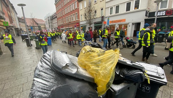 Streikende auf dem Weg zu einer Kundgebung in Göttingen, im Vordergrund stehen ungeleerte Mülltonen. © NDR Foto: Jan Fragel