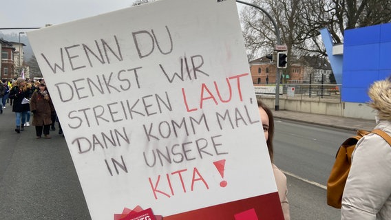 Ein Frau hält bei einer Kundgebung in Hameln ein Schild mit dem Text "Wenn du denkst, wir streiken laut, dann komm mal in unsere Kita" hoch. © NDR Foto: Wolfgang Kurtz