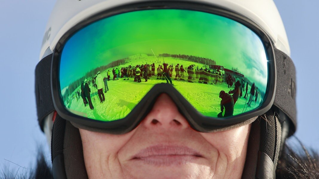 Der Wurmberg spiegelt sich in einer Skibrille einer Skifahrerin.