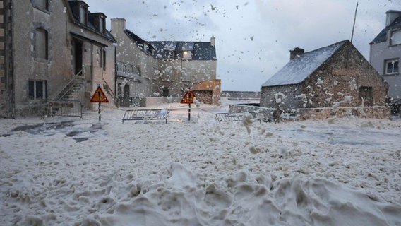 Während eines Sturms strömen Schaum und Nebel über eine Straße in Penmarche, Frankreich.  © Fred Tano/AFP/DPA Fotografie: Fred Tano