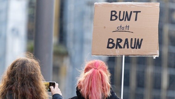 "Bunt statt braun" steht auf dem Pappschild einer jungen Frau, die an einer Kundgebung gegen Rechtsextremismus teilnimmt. © picture alliance/dpa | Henning Kaiser Foto: Henning Kaiser
