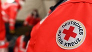 Ein Logo des Deutschen Roten Kreuz (DRK) an einer Jacke, die ein ehrenamtlicher Mitarbeiter trägt. © picture alliance/dpa Foto: Uli Deck