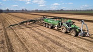 Ein Landwirt bringt Gülle mit Schleppschlauchtechnik auf einem Acker aus. © picture alliance/Countrypixel | FRP 