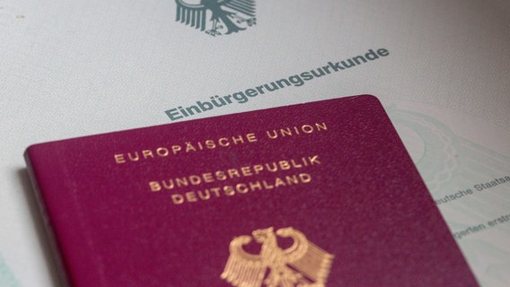 Eine Einbürgerungsurkunde der Bundesrepublik Deutschland und ein deutscher Reisepass liegen auf einem Tisch. © dpa-Bildfunk Foto: Fernando Gutierrez-Juarez