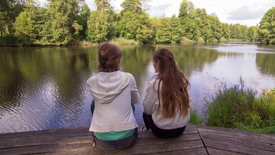 Zwei jungen Frauen sitzen an einem See © NDR 