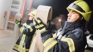 Zwei Feuerwehrleute halten einen Wasserschlauch in der Hand. © NDR Foto: Julius Matuschik