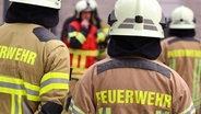 Auf dem Rücken zweier Einsatzkräfte steht "Feuerwehr". © dpa - picture alliance Foto: Tino Plunert