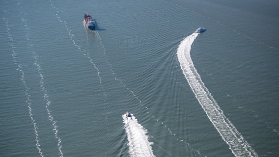 Ein Frachtschiff und andere Schiffe fahren an Borkum vorbei. © dpa-Bildfunk Foto: Sina Schuldt