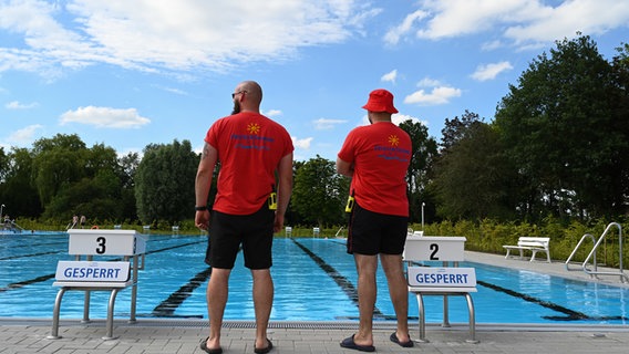 Zwei Sicherheitsmitarbeiter des Freibad Borssum überblicken das Schwimmbecken. © picture alliance/dpa/Lars Penning Foto: Lars Penning