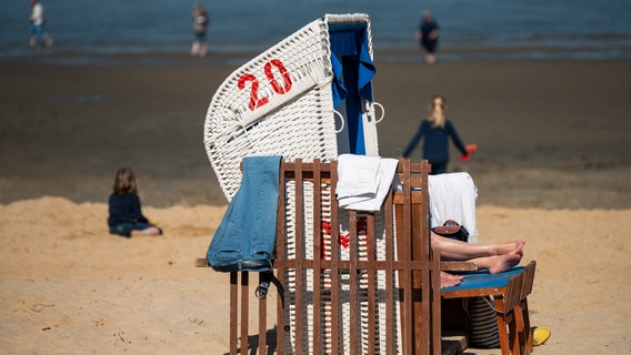 Menschen und ein Strandkorb am Strand von Cuxhaven bei sonnigen Wetter © picture alliance Foto: Mohssen Assanimoghaddam