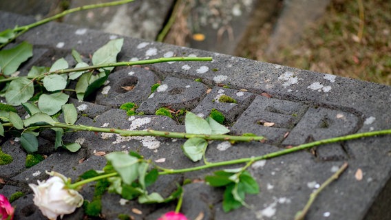 Rosen liegen während einer Gedenkveranstaltung am ehemaligen Standort der Synagoge im Stadtzentrum von Oldenburg auf einer Gedenkstätte. © picture alliance Foto: Hauke-Christian Dittrich