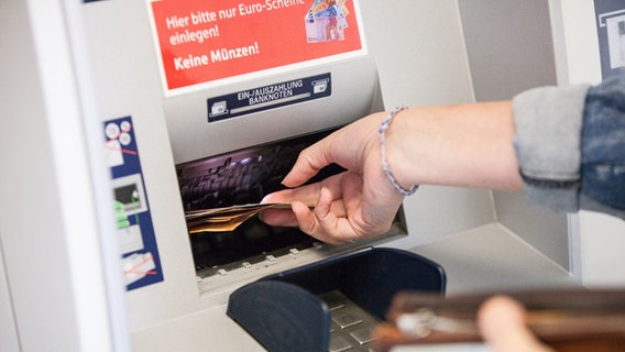 Eine Frau hebt an einem Bankautomaten Bargeld ab. © picture alliance/Fotostand/K. Schmitt Foto: K. Schmitt