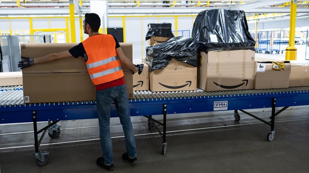 Ein Amazon-Mitarbeiter steht an einem Fließband.
