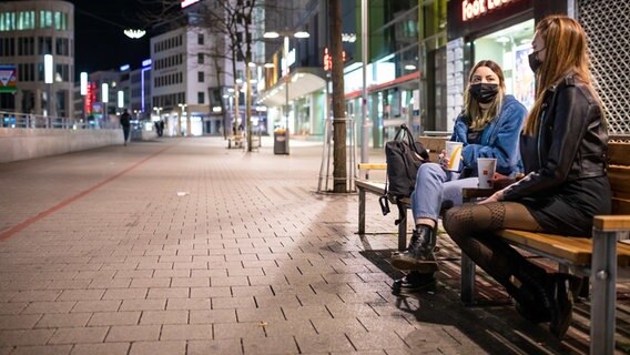 Hannover: Zwei Freundinnen unterhalten sich, auf einer Bank in der Innenstadt sitzend, am Abend. © dpa-Bildfunk Foto: Moritz Frankenberg