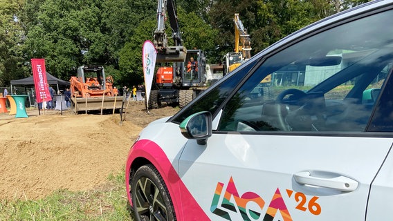 Auf einem Auto ist das Logo der 8. Niedersächsische Landesgartenschau zu sehen, im Hintergrund ein Bagger. © NDR Foto: Wolfgang Kurtz