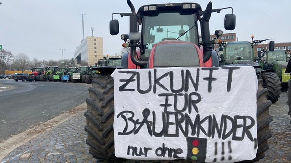 Auf einem Traktor ist ein Plakat mit dem Slogan "Zukunft für Bauernkinder nur ohne Ampel" zu lesen. © NDR Foto: Tanja Niehoff