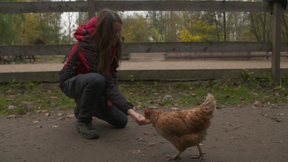 Ein Mädchen füttert ein Huhn. © NDR 