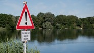 Ein Schild "Vom Baden wird abgeraten - Blaualgen" steht am Hohnsensee. © dpa-Bildfunk Foto: Julian Stratenschulte