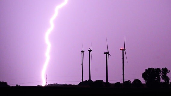 Ein Blitz vor einem lila Himmel. Daneben sind Windkraftanlagen zu sehen. © picture alliance/dpa | Julian Stratenschulte Foto: picture alliance/dpa | Julian Stratenschulte