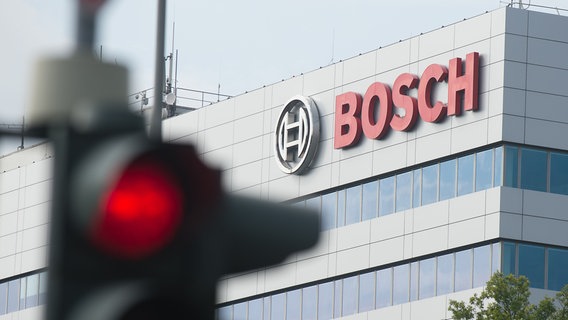 Der Schriftzug "Bosch" ist in Hildesheim (Niedersachsen) auf einem Gebäude des Bosch-Werks hinter einer roten Ampel zu sehen © picture Alliance / dpa Foto: Swen Pförtner