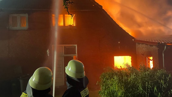 Zwei Feuerwehrleute löschen ein brennendes Haus mit einem Schlauch. © Freiwillige Feuerwehr Stadt Rehburg-Loccum Foto: Till Scheibner