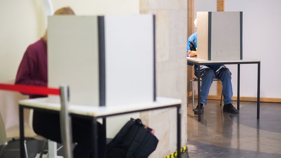 Eine Frau und ein Mann füllen ihre Stimmzettel für die Bundestagswahl und Kommunalwahlen in Wahlkabinen im Neuen Rathaus aus. © dpa-Bildfunk Foto: Julian Stratenschulte