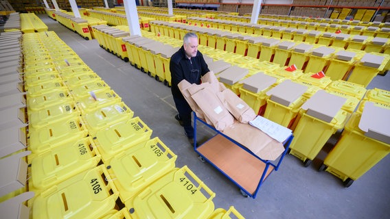 Thomas Rittler, Mitarbeiter im Wahlamt der Stadt Hannover, läuft im Wahllager der Stadt Hannover zwischen Urnen, die unter anderem für die Bundestagswahl 2025 genutzt werden. © dpa-Bildfunk Foto: Julian Stratenschulte